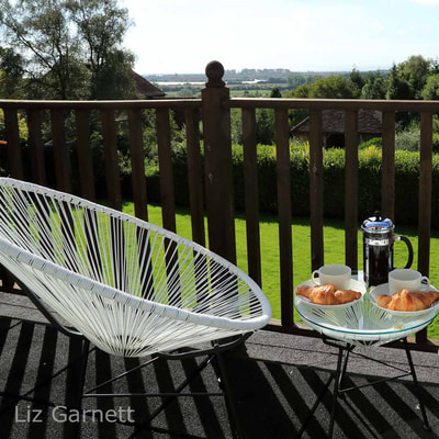 Professional property photography of breakfast scene on balcony overlooking Romney Marsh in Kent by Liz Garnett
